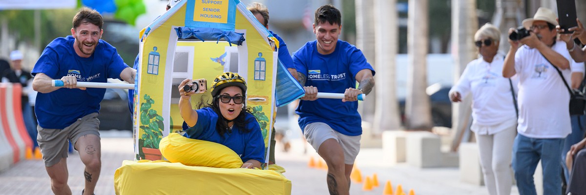 Two participants push a brightly decorated bed carrying a teammate during the Sprint for Seniors Bed Race.