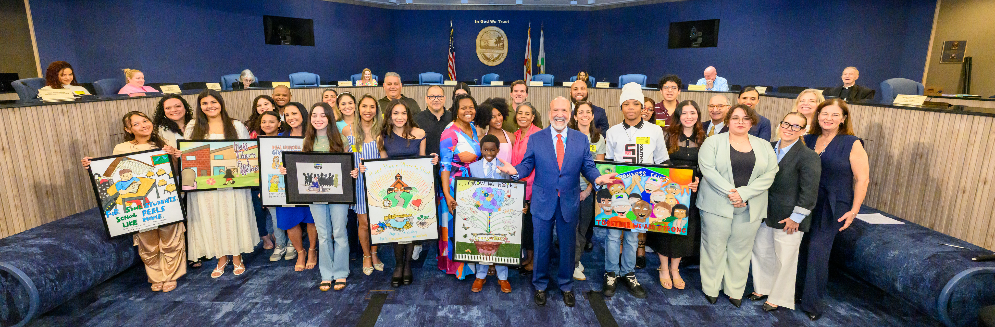 Students and board members holding up their winning art at the Trust's March board meeting